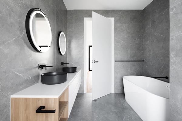 Baño de mármol con bachas de apoyo y mueble de madera